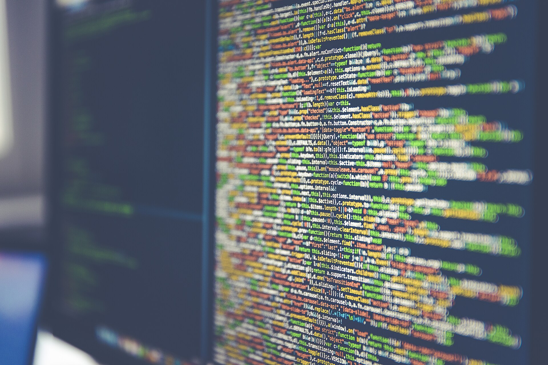 JavaScript source code on a monitor, colour-highlighted, shot at an angle